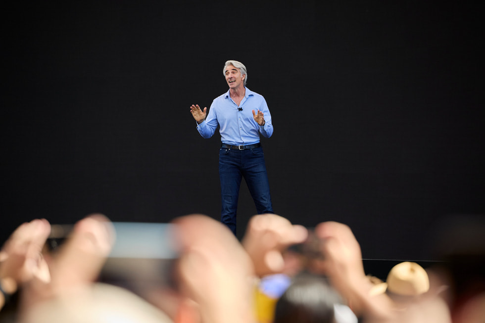 Craig Federighi stands on a stage at at Apple Park on the opening day of WWDC24.