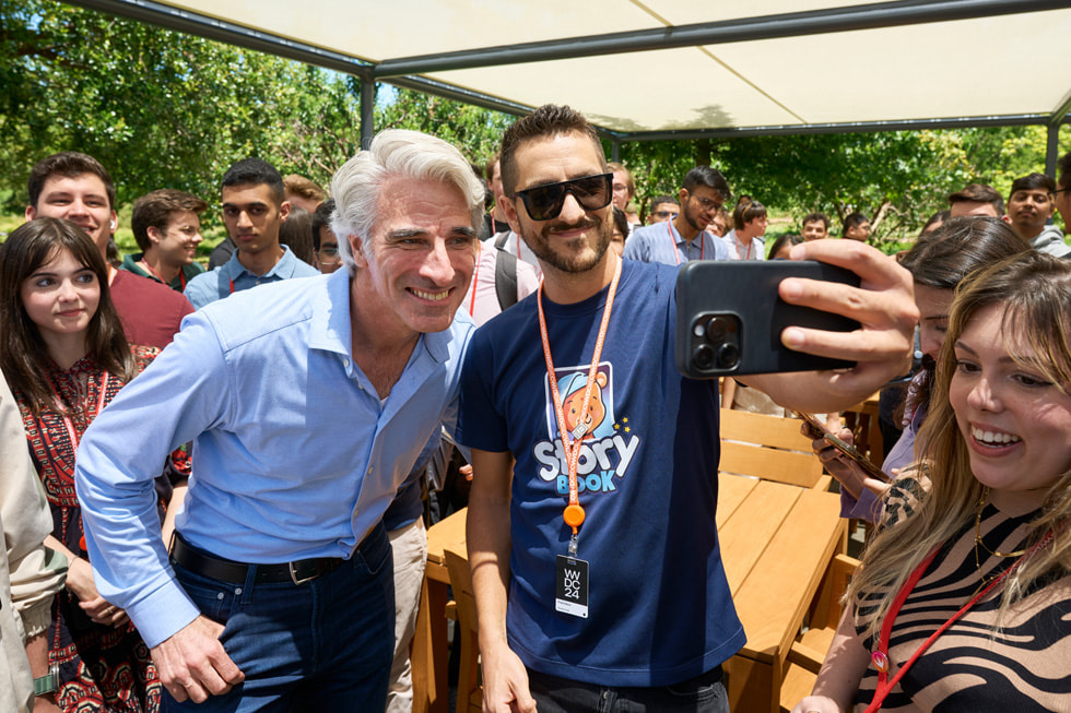 Craig Federighi umgeben von Entwickler:innen posiert für Selfies im Apple Park.