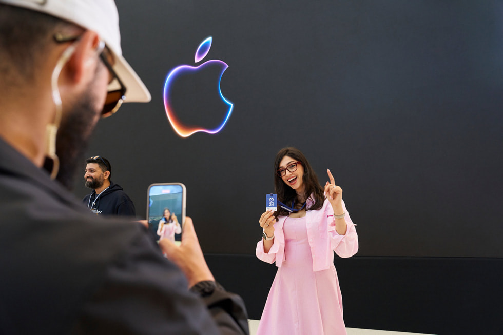 一名 Apple 團隊成員為一名持 WWDC24 入場證擺姿勢的參與人士拍照。 