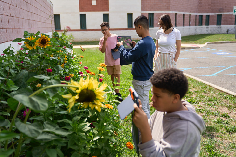 STEM Explorers camp participants use the camera on iPad in a garden.