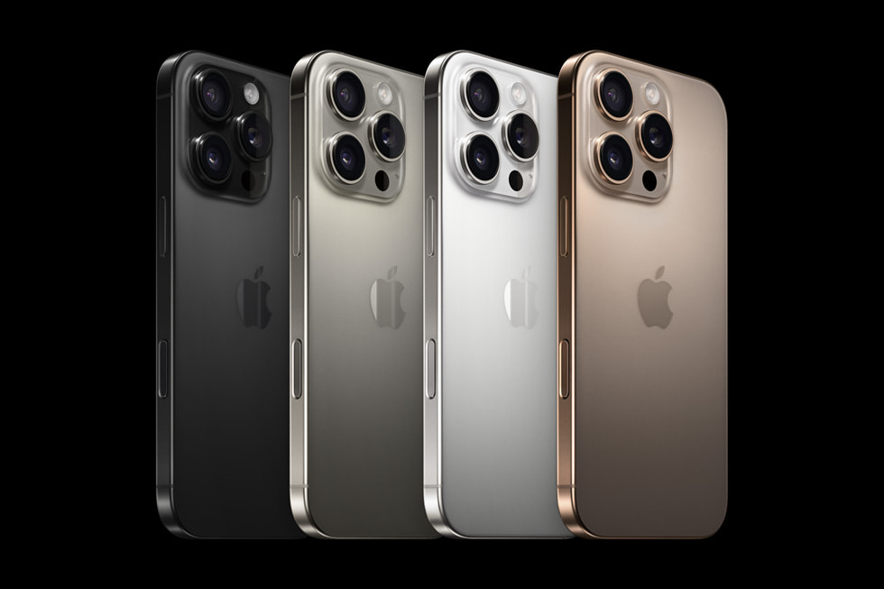 Un primo piano di quattro iPhone 16 Pro in quattro finiture diverse: titanio nero, titanio naturale, titanio bianco e titanio sabbia.