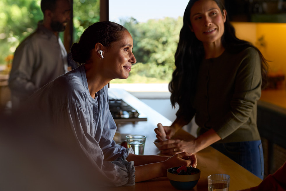 Et livsstilsbillede viser en person med AirPods Pro 2, der lytter til andre personer.