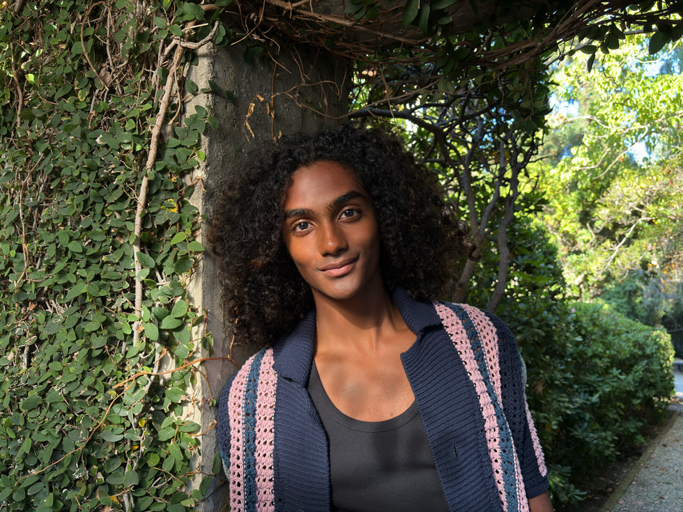 A headshot shows a person with foliage in the background.