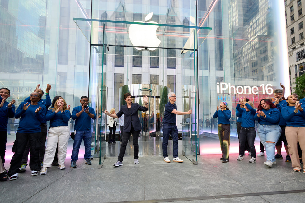 Deirdre O’Brien and Tim Cook stand in front of Apple Fifth Avenue in New York City as a queue of excited customers looks on.