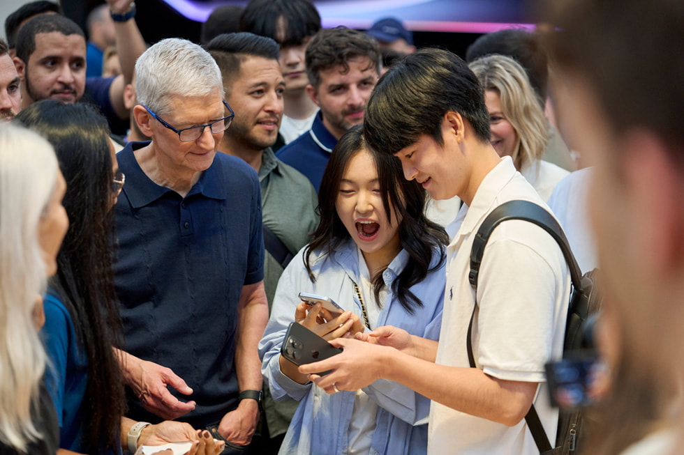 Tim Cook stands with customers inside Apple Fifth Avenue in New York City.