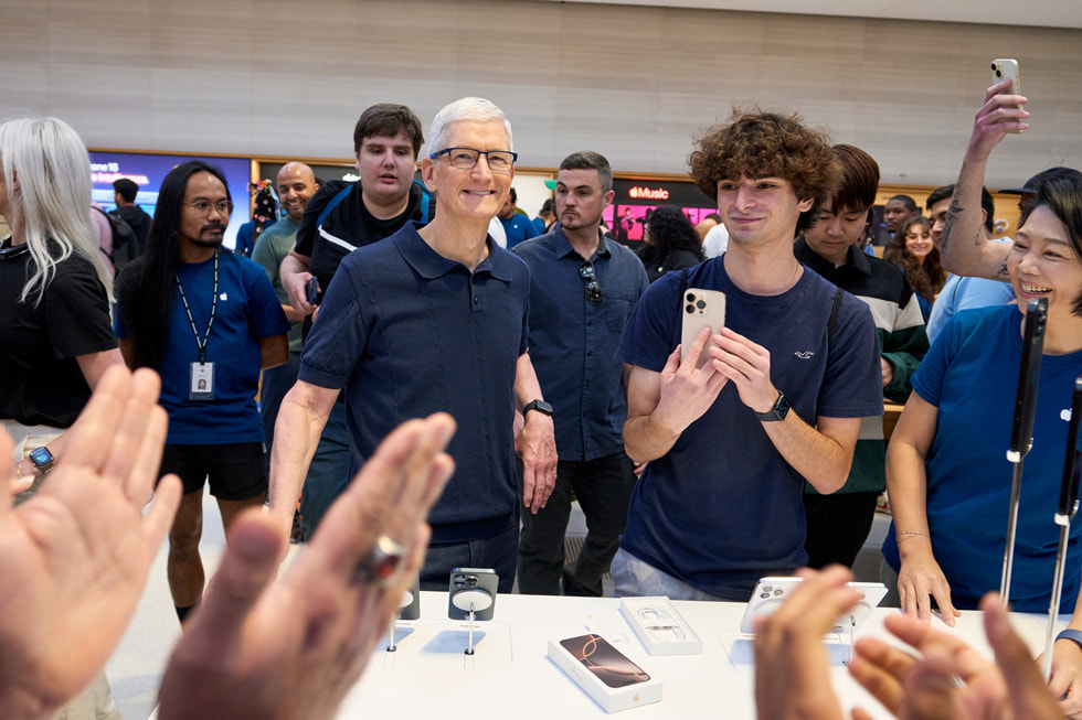 Tim Cook smiles and poses with customers and team members at Apple Fifth Avenue in New York City.