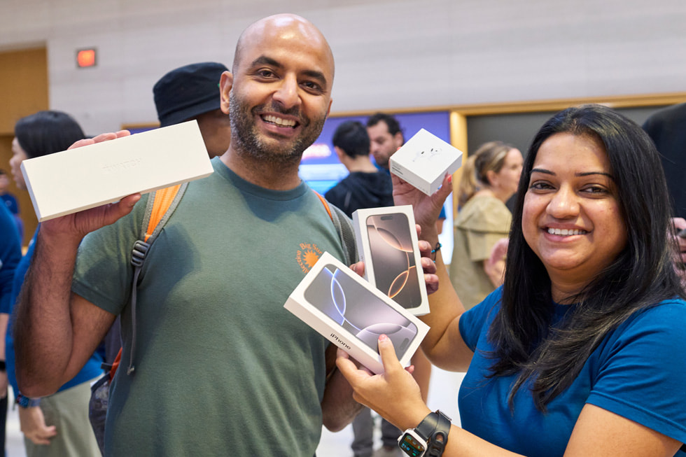 A customer and a team member display new products — including devices from the iPhone 16 lineup — at Apple Fifth Avenue in New York City.