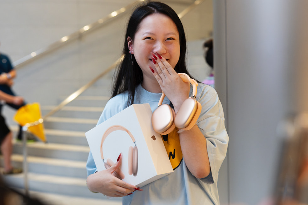 A customer smiles bashfully with their new AirPods Max purchase.