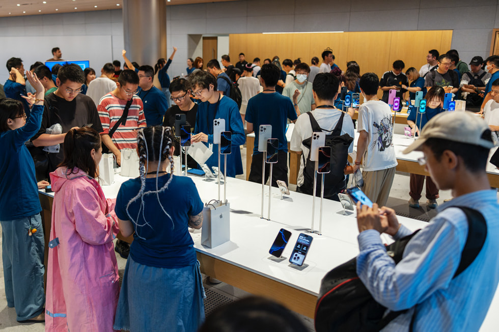 A crowd of customers test out the new iPhone 16 lineup.