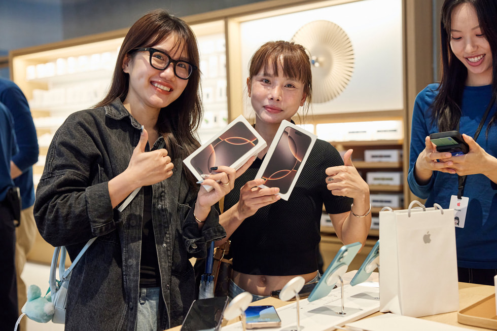 Customers show off their new iPhone 16 Pro purchases.