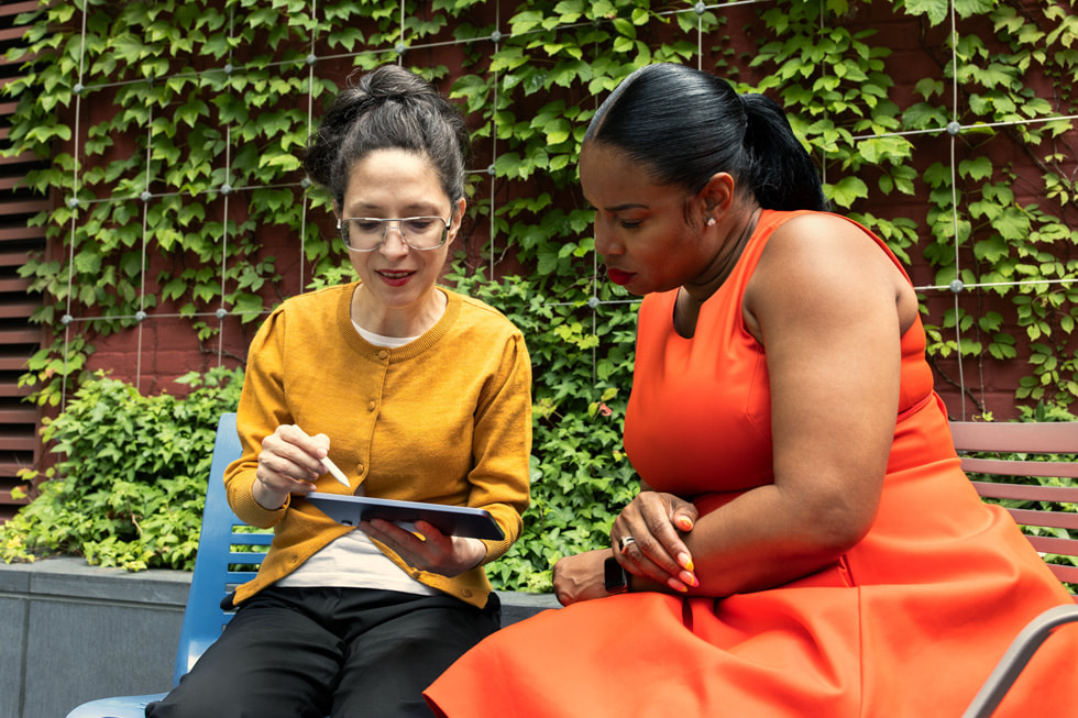 Holding an iPad and Apple Pencil, New York Public Library patron Evelyn von Gizycki sits outdoors with NYPL's Dr. Brandy McNeil.