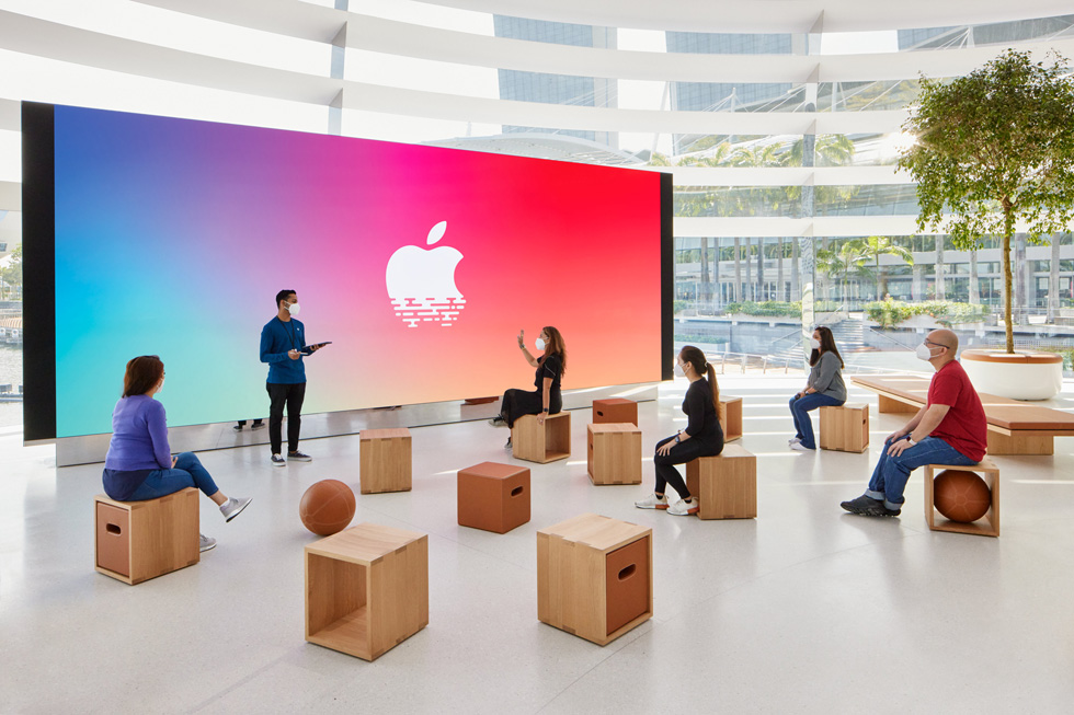 Een groepje klanten zit naar een Apple medewerker te luisteren.