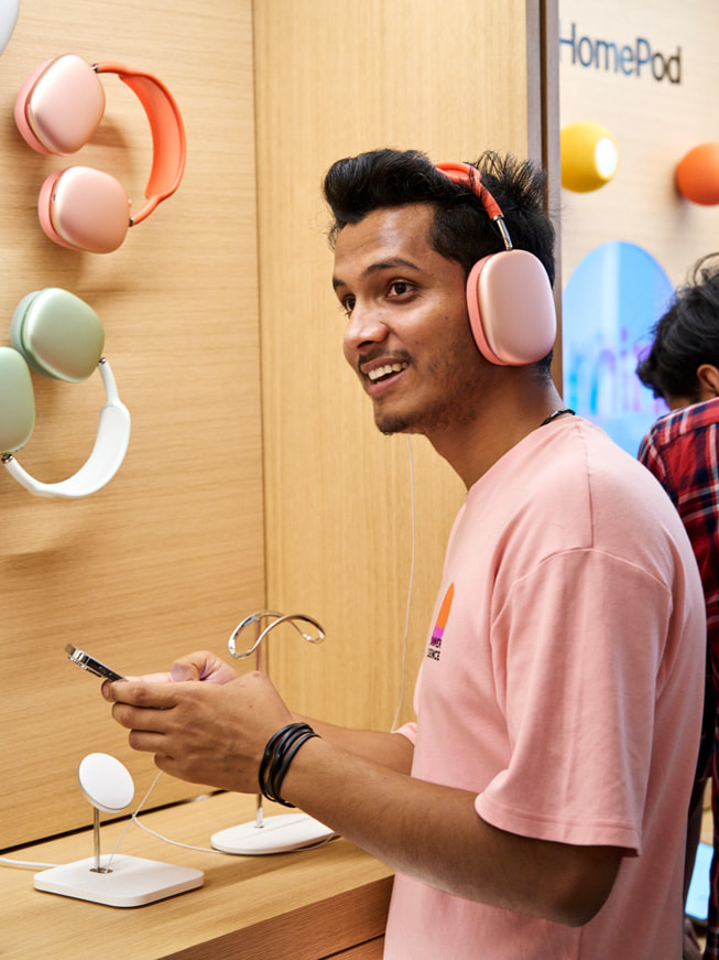A customer tests out AirPods Max in front of the store's display.
