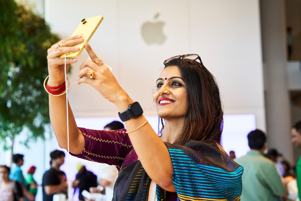 Una clienta se toma una selfie con un iPhone 14 amarillo.