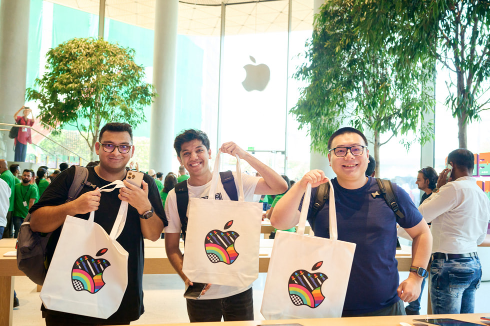 Des clients posent avec des sacs réutilisables Apple. 