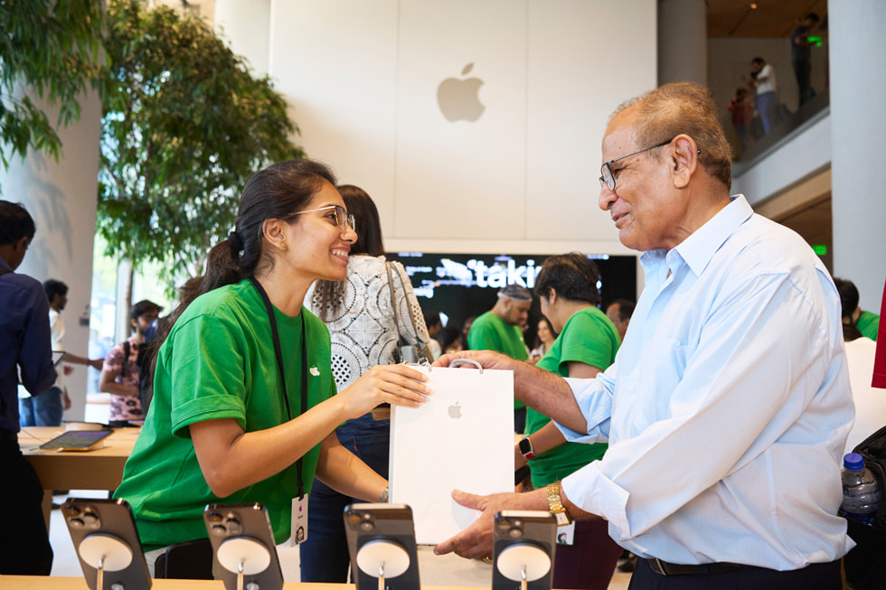 Una miembro del equipo de Apple BKC le entrega su compra a un cliente. 