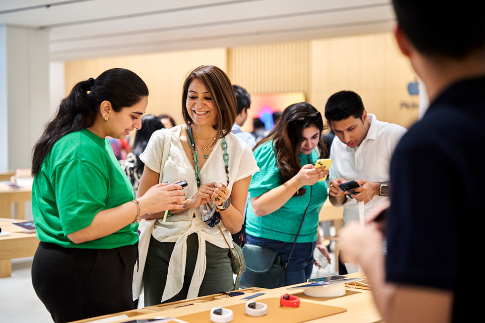 En medarbeider hjelper en kunde foran en utstilling med de nyeste Apple Watch-modellene.