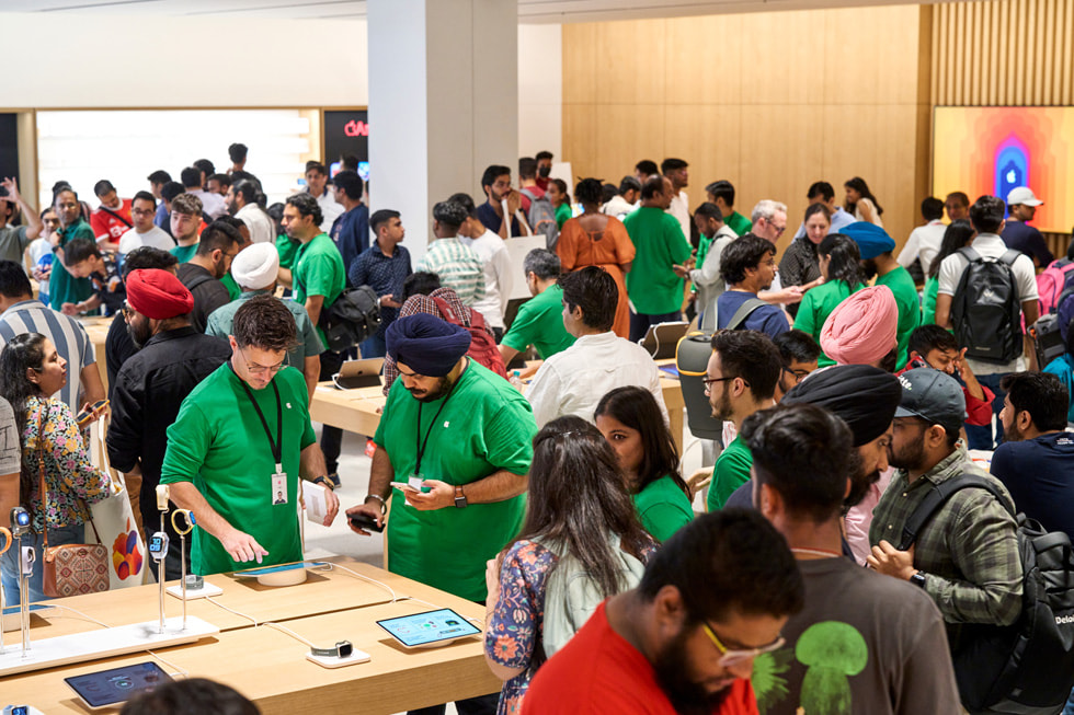 Inside of Apple Saket, customers speak with Apple team members and gather around tables to explore the store's many devices.