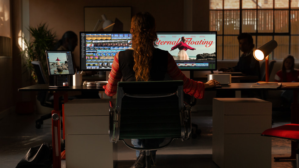 A person in a loft-style workspace uses Mac Studio and Mac Pro.