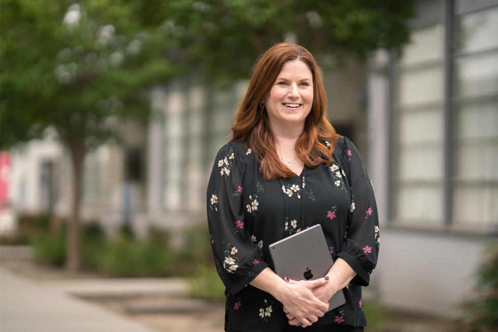 Jennifer Robbins, dyrektorka ds. edukacji podstawowej w okręgu Downey Unified i specjalistka Apple Learning Coach, stoi na dworze i trzyma iPada.