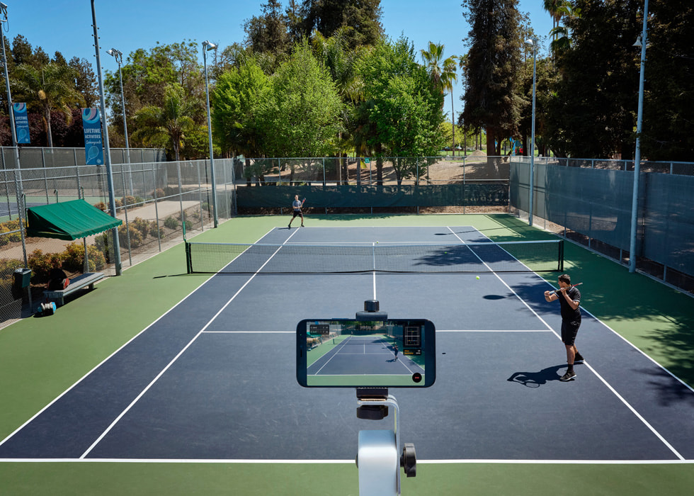 Un iPhone colocado para grabar a dos personas jugando en una pista de tenis.
