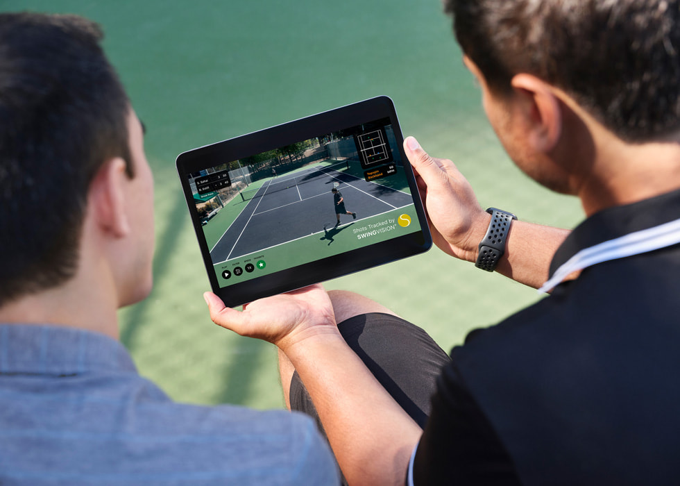 Sahai sostiene un iPad que muestra imágenes grabadas de un partido mientras él y su oponente miran.