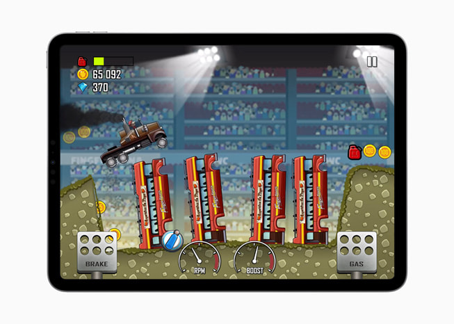 Một ảnh tĩnh từ trò chơi Hill Climb Racing+ với một chiếc xe tải quái vật nhảy qua một cái hố chứa đầy xe cứu hỏa trên iPad Pro.