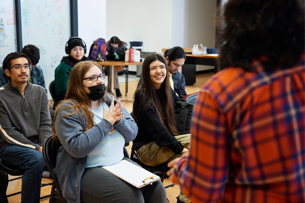 Wykładowczyni Jessica „Jess” Jerome sfotografowana zza pleców, gdy rozmawia ze studentami w sali na uczelni. 