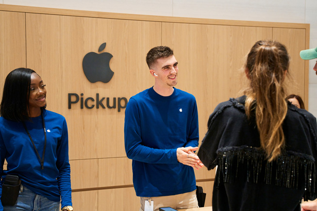 Apple 團隊成員在 Apple Store 零售店的 Apple Pickup 專區協助顧客自取預訂的產品。