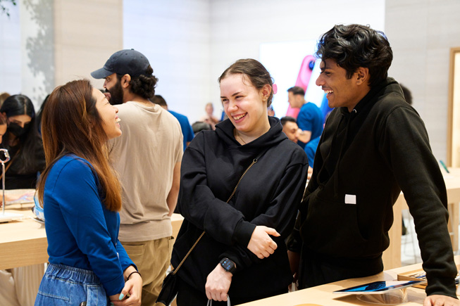 Apple team members and customers converse at an Apple Store.