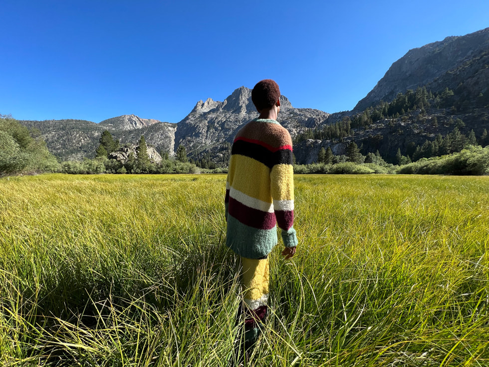Un hombre en un paisaje colorido y frondoso, tomado con la cámara gran angular del iPhone 13 Pro.