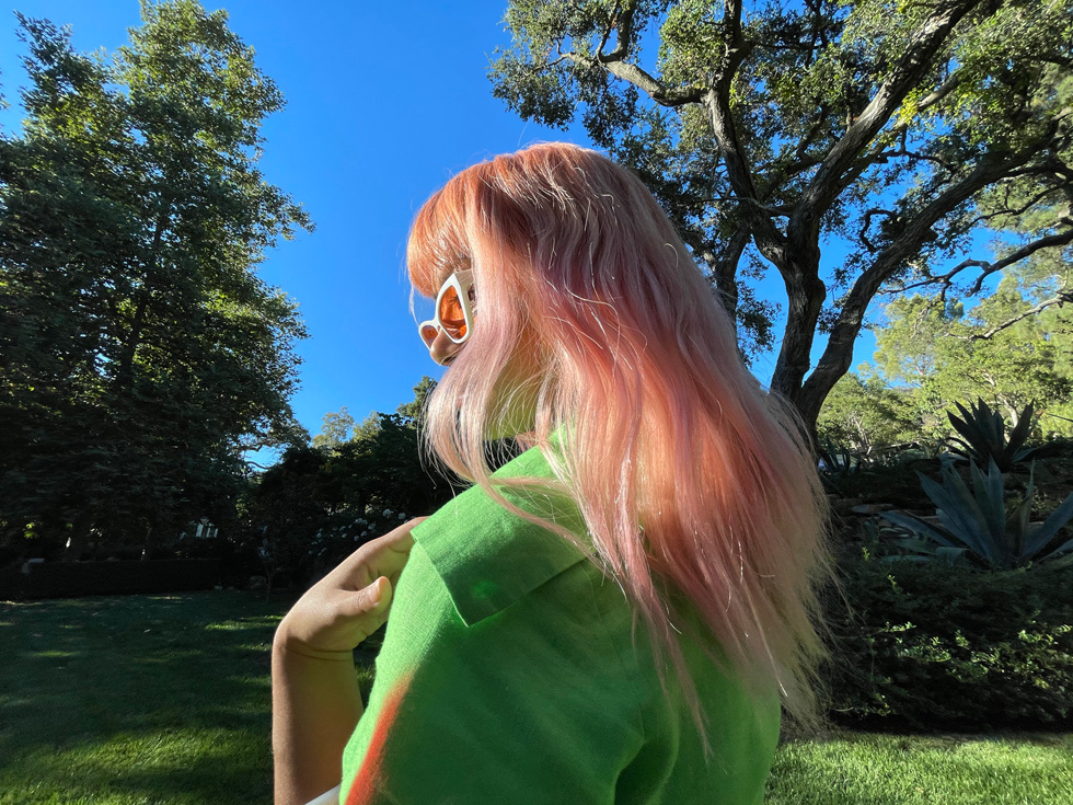 Une femme aux cheveux roses photographiée avec la caméra ultra grand-angle d’iPhone 12 Pro.