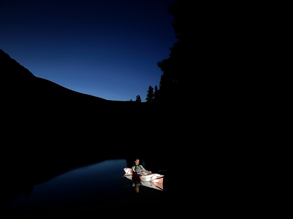 以 iPhone 13 的廣角相機，使用夜間模式拍攝一位男子於獨木舟上的夜間相片。
