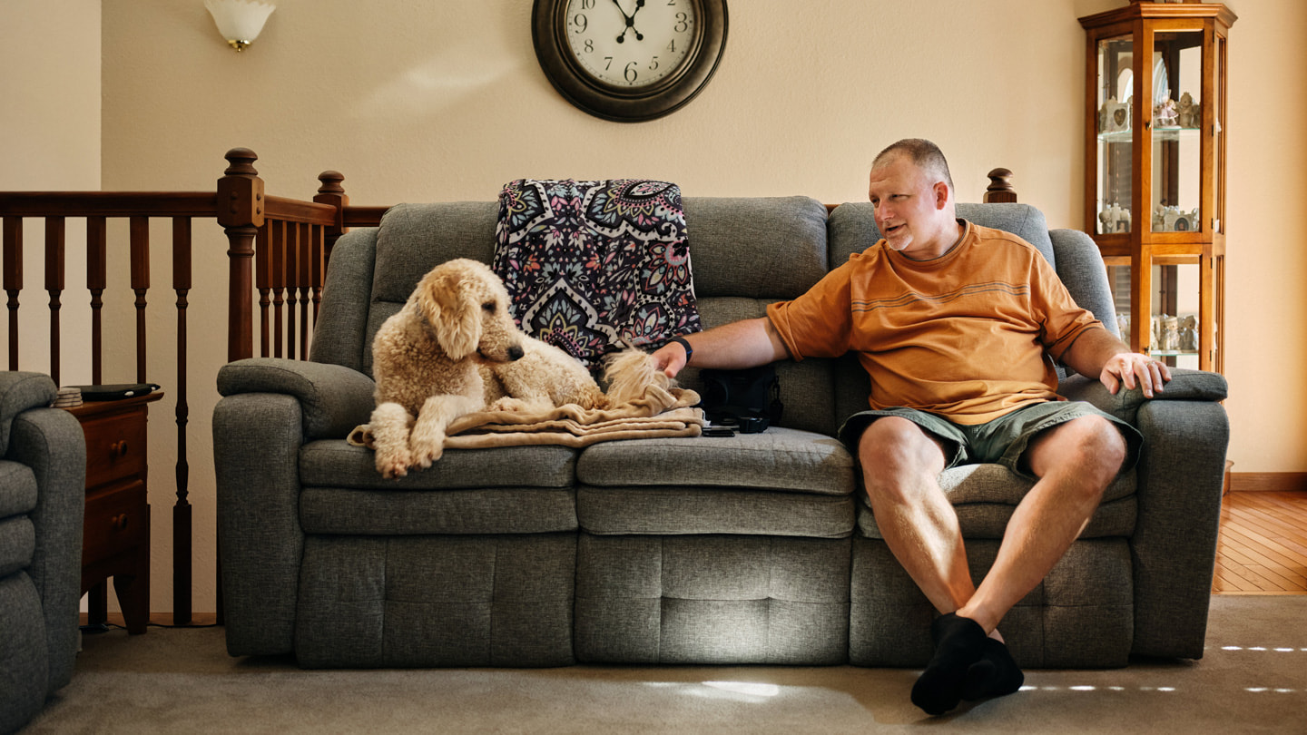 صورة لروبرت غيثز في منزله على الأريكة مع كلبه.