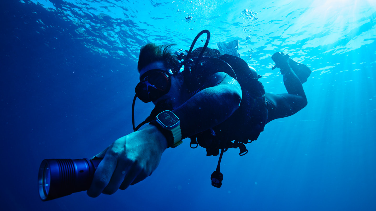Un plongeur porte une Apple Watch Ultra équipée d’Oceanic+ et nage sous la surface de l’océan.