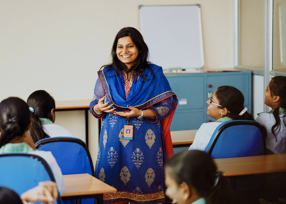 Una mujer enseña a alumnos en un aula.