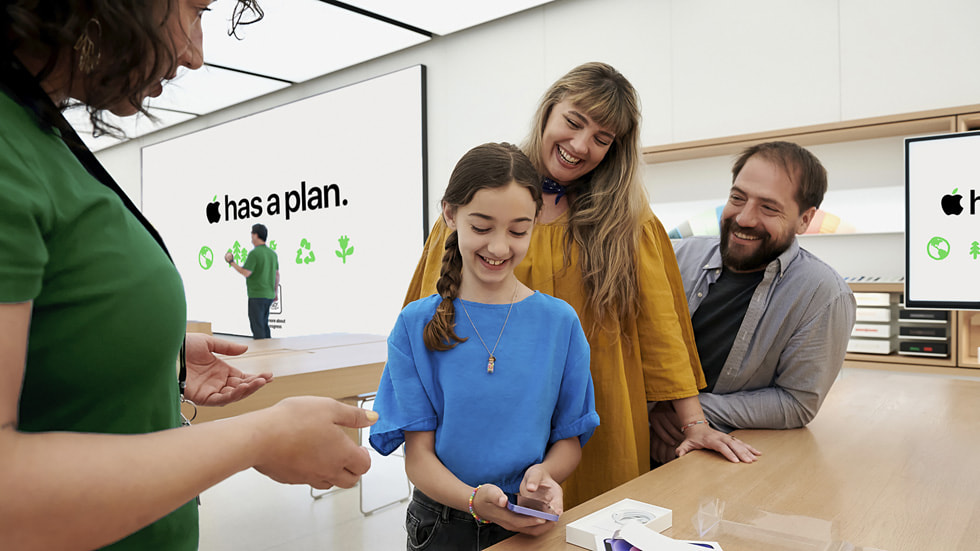 Dois clientes adultos e uma cliente jovem conversam com uma funcionária da Apple Store.