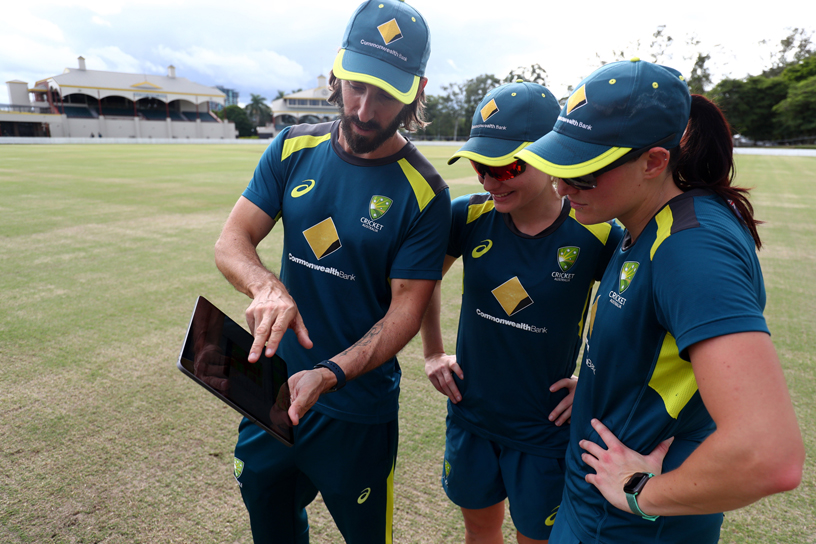 Australia Women’s Cricket Team player and coach reviewing performance stats on iPad.