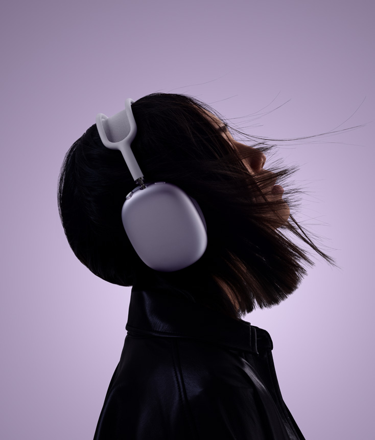 A woman's head, shot from the side. She's looking slightly up and wearing AirPods Max.