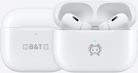 예시로 각인이 새겨진 AirPods 4 충전 케이스 두 개의 모습. 텍스트 ‘B&T’ 및 텍스트 양쪽 끝에 고양이 이모티콘이 새겨져 있는 케이스 하나와 게 이모티콘이 새겨져 있는 또 다른 케이스 하나