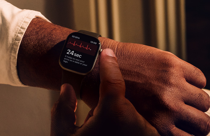 Човек натиска и задържа Digital Crown на Apple Watch Series 11, за да измери сърдечното здраве в EКГ приложението