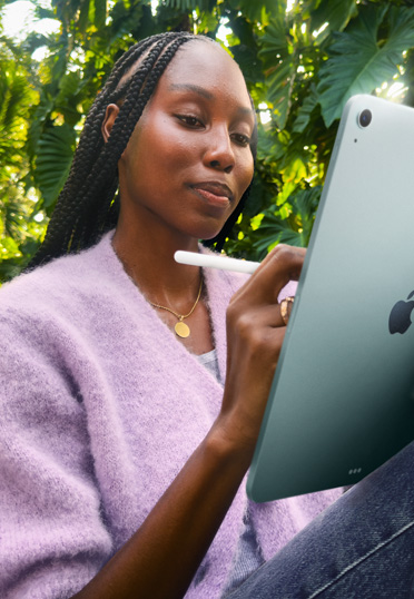 นักศึกษานั่งอยู่กลางแจ้ง พร้อมถือ iPad และ Apple Pencil Pro ในมือ