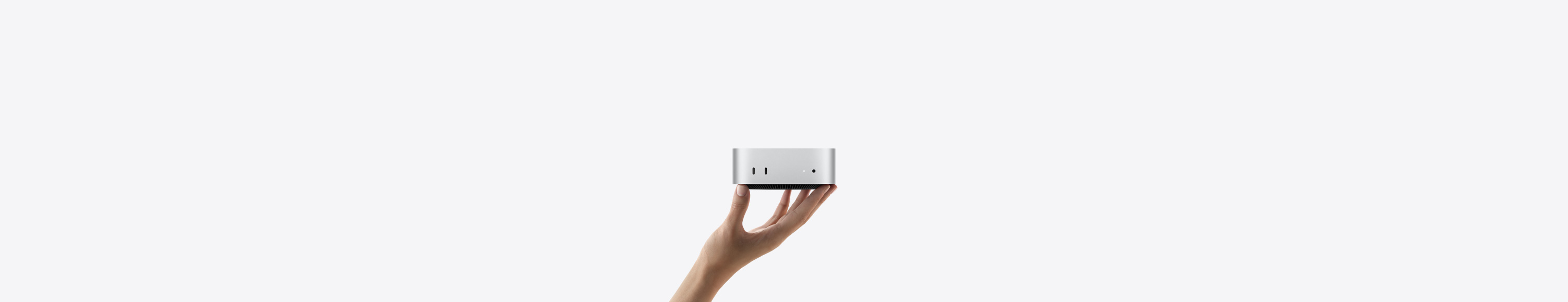 Vista frontal de un Mac mini sobre las puntas de los dedos de una mano estirada, con dos puertos Thunderbolt, luz indicadora de estado y entrada para audífonos, base cónica negra en la parte inferior, superficie plana en la parte superior, lados redondeados, bordes rectos, color plata