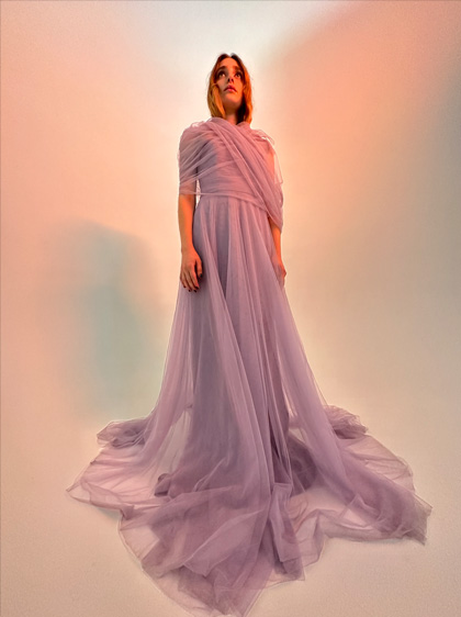 Una foto de una mujer con un largo vestido morado. La foto fue tomada con poca luz en la cámara Ultra Wide.