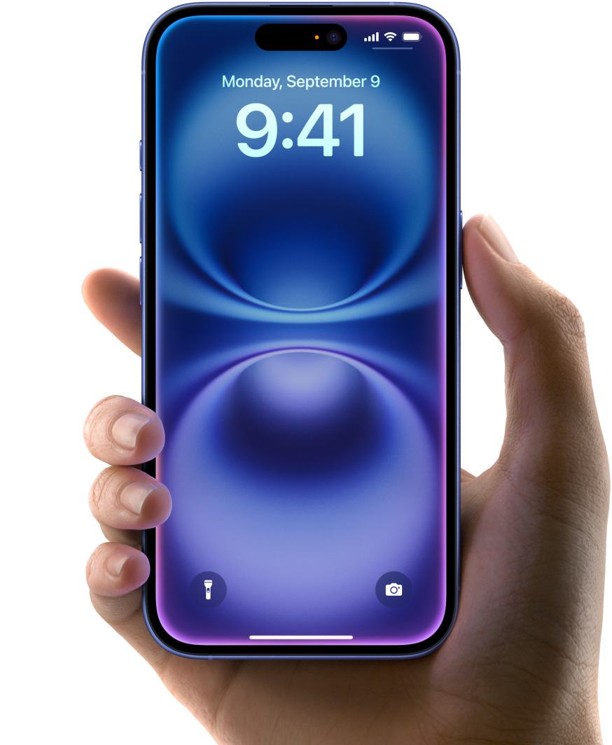 Egy kéz egy ultramarin színű iPhone 16-ot tart, a készülék egész előlapot betöltő kijelzővel, a felül középen található Dynamic Islanddel és lekerekített sarkokkal rendelkezik