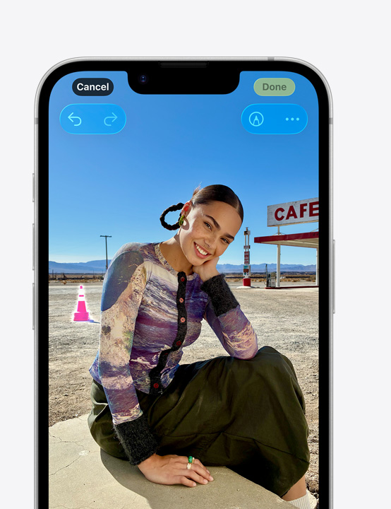iPhone 螢幕上是一個人在沙灘上面露微笑的照片,展示如何使用清除工具移除背景中的交通錐