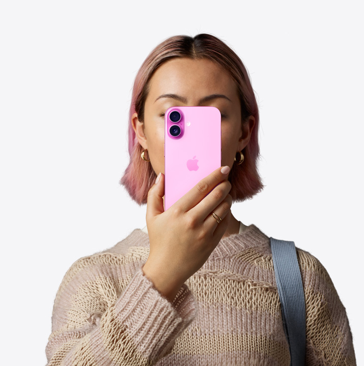 一位女性將粉紅色 iPhone16 舉在面前,展示機身背面和位於左上角的雙相機系統。