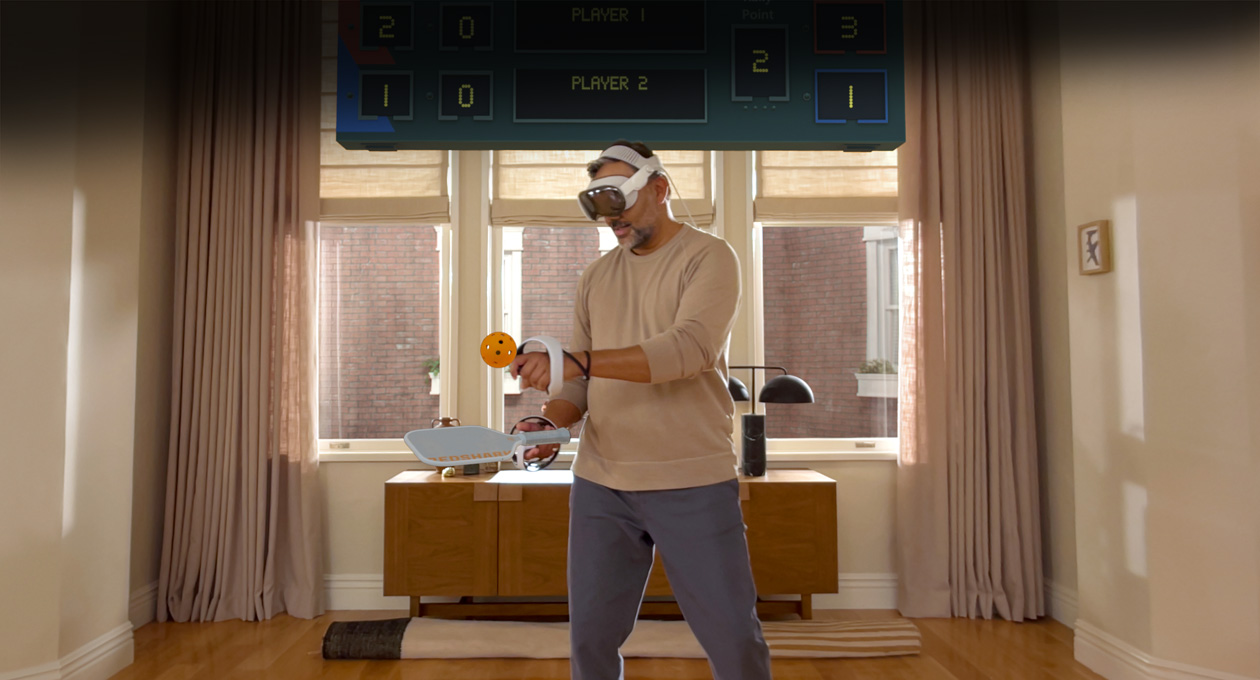 一位男士邊戴著 Apple Vision Pro,邊拿著 Sony PlayStation VR2 Sense 控制器在玩:《Pickle Pro》,空間計分板就在他的頭上