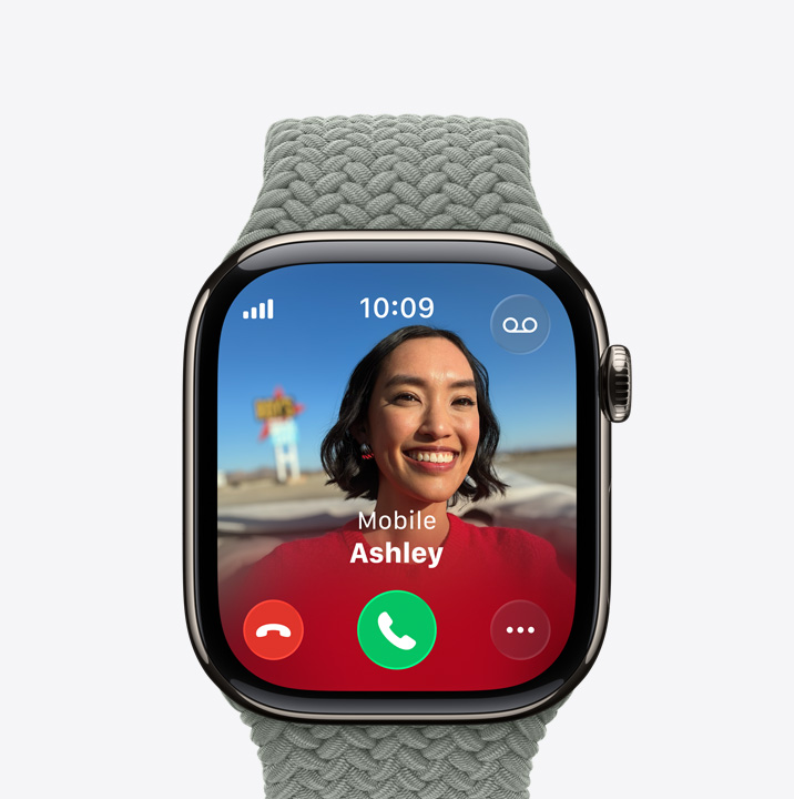 Vista lateral direita do Apple Watch Series 11, com caixa em titânio natural, ecrã com chamada recebida, fotografia do contacto e botões Aceitar e Recusar, Digital Crown e Bracelete Solo entrançada na cor floresta